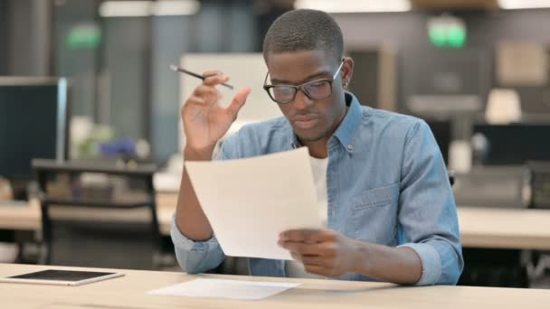 Giovane uomo afroamericano che celebra durante la lettura di documenti — Video Stock