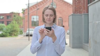 Sokakta yürürken akıllı telefon kullanan güzel bir kadın.