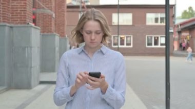 Sokakta yürürken akıllı telefon kullanan kadın