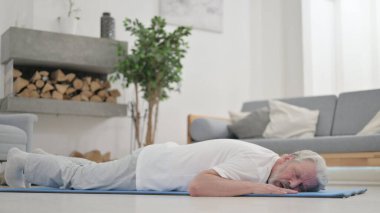 Şınav çektikten sonra yorgun yaşlı adam yatıyor.