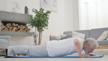 Yaşlı adam evde egzersiz yaparken şınav çekiyor.