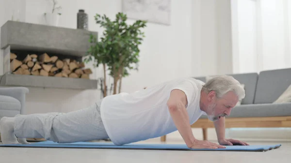 Fáradt öregember csinál fekvőtámaszt a matracon otthon. — Stock Fotó