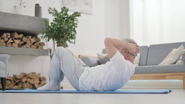 Yaşlı adam evde egzersiz yapıyor, karın egzersizi.