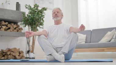 Yaşlı adam kulaklıkla müzik dinliyor ve meditasyon yapıyor. 