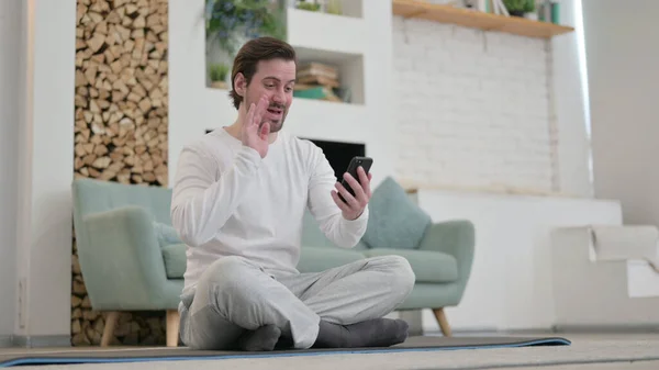 Jongeman praten op video bellen op Smartphone tijdens het zitten op Yoga Mat — Stockfoto
