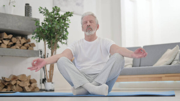 Peaceful Old Man Meditating on Excercise Mat at Home