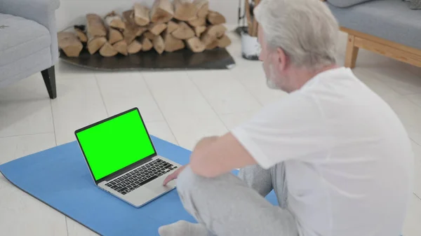 Starý muž pomocí notebooku se zelenou obrazovkou na cvičení matice — Stock fotografie