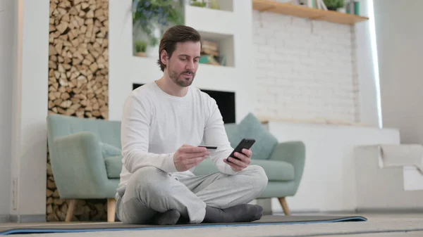 Mladý muž dělá on-line nakupování na Smartphone na Yoga Mat — Stock fotografie