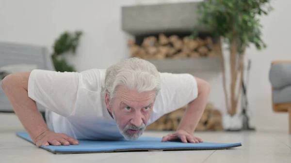 Nahaufnahme eines alten Mannes, der zu Hause Liegestütze auf der Trainingsmatte macht — Stockfoto