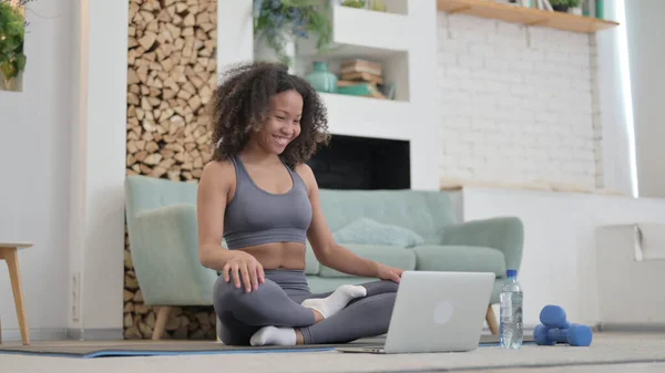 Ung afrikansk kvinna talar på video Ring på laptop medan du är på Yogamatta — Stockfoto