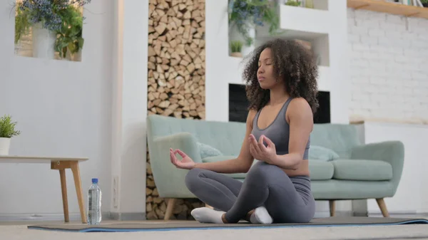 Ung afrikansk kvinna gör meditation på träningsmatta hemma — Stockfoto
