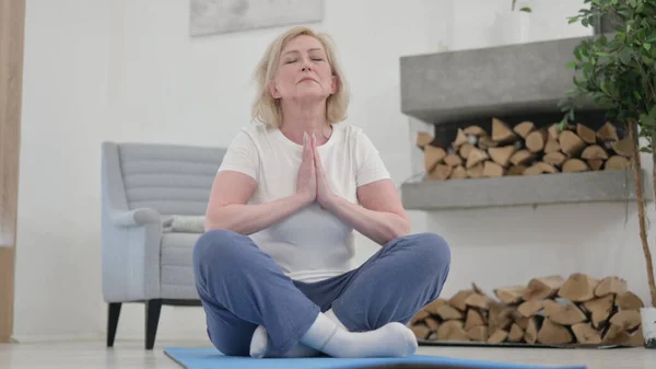 Gammal kvinna som gör yoga på träningsmatta hemma — Stockfoto