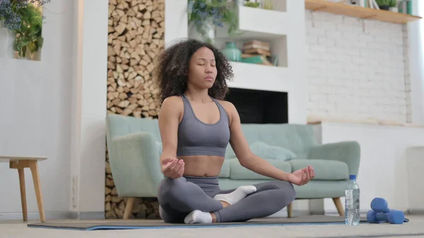 Jovem mulher africana meditando no tapete excerciso em casa — Fotografia de Stock