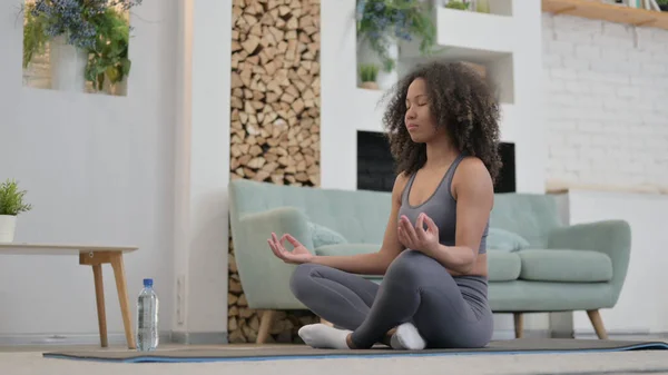 Jovem mulher africana pacífica meditando no tapete excercise em casa — Fotografia de Stock