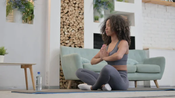 Fredlig ung afrikansk kvinna mediterar på träningsmatta hemma — Stockfoto