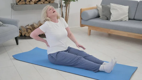 Gammal kvinna som har ont i ryggen när hon gör yoga hemma — Stockfoto