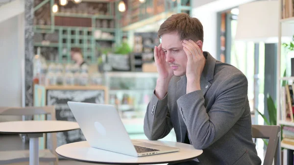 Dizüstü bilgisayarı olan genç adam baş ağrısı çekiyor. — Stok fotoğraf