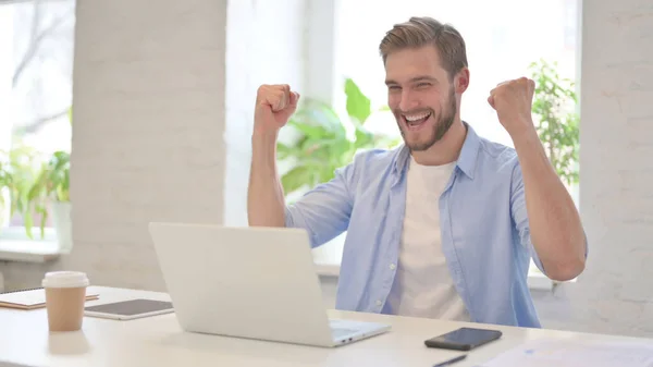 Successful Young Man Celebrating on Laptop in Modern Office