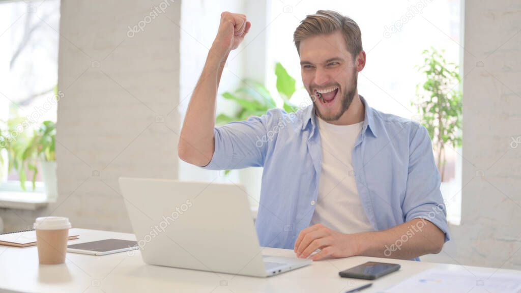 Young Man Celebrating Win in Modern Office 