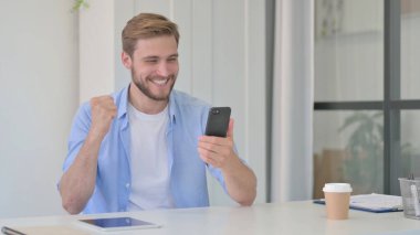 Ofisteki Akıllı Telefon 'da Başarıyı Kutlayan Genç Adam 