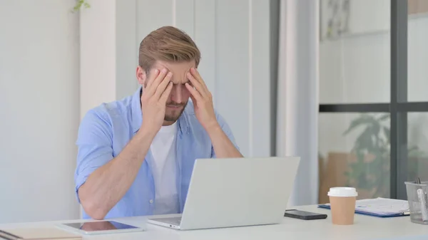 Junger Mann hat Kopfschmerzen bei der Arbeit — Stockfoto