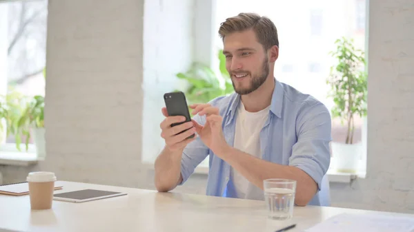 Mladý muž používající smartphone v moderní kanceláři — Stock fotografie