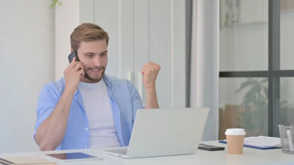 Wütender Mann mit Laptop spricht auf Smartphone — Stockfoto