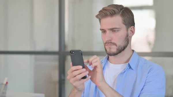 Mladý muž Browing Internet na Smartphone — Stock fotografie