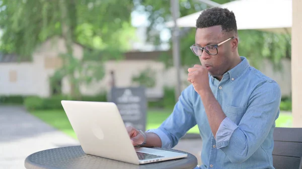 Laptop 'u olan Afrikalı adam öksürüyor. — Stok fotoğraf
