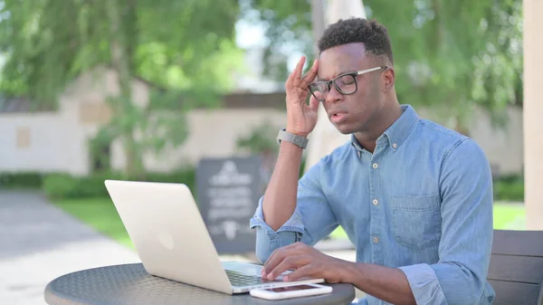Homem africano com laptop com dor de cabeça ao ar livre — Fotografia de Stock