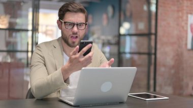 Dizüstü bilgisayarı olan agresif adam telefonda sinirleniyor. 