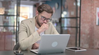 Genç adam işte öksürüyor. 