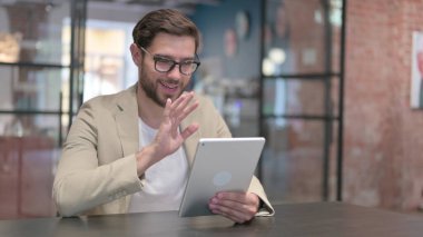 Genç adam iş yerindeki tablete video çağrısı yapıyor. 