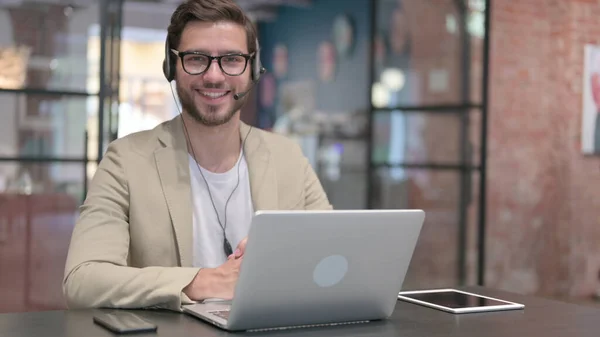 Kulaklıklı ve laptoplu bir adam Kameraya gülümsüyor — Stok fotoğraf