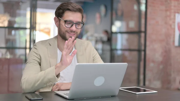 Giovane uomo parlando in videochiamata sul computer portatile al lavoro — Foto Stock