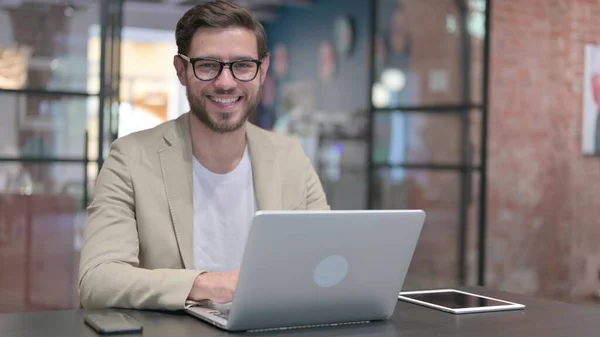 Giovane uomo con computer portatile sorridente alla fotocamera — Foto Stock