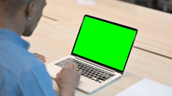 Hombre africano usando el ordenador portátil con la pantalla dominante verde del croma —  Fotos de Stock