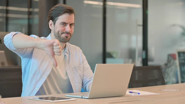 Polegares para baixo por homem com laptop no escritório — Fotografia de Stock