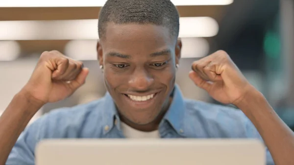 Framgångsrik ung afrikansk man firar på laptop — Stockfoto