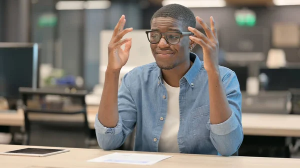 Rozrušený mladý Afričan znepokojený, když sedí v kanceláři — Stock fotografie