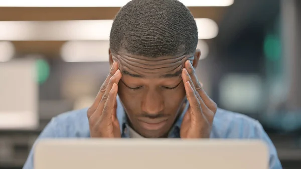 Mladý Afričan s bolestí hlavy pracující na notebooku — Stock fotografie
