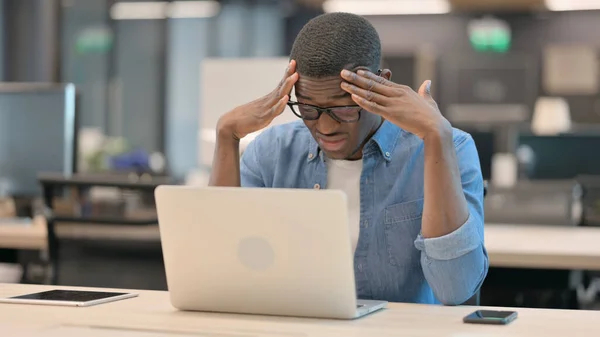 Mladý Afričan s bolestí hlavy pracující na notebooku — Stock fotografie