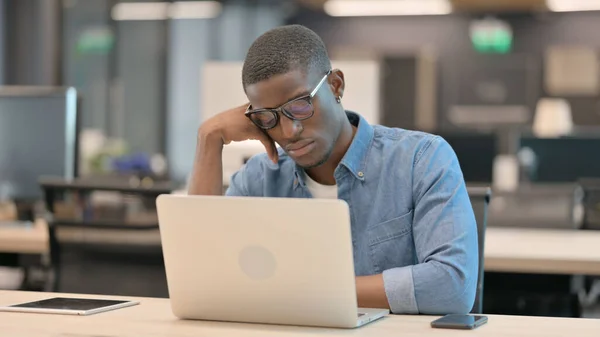 노트북을 가지고 있는 젊은 아프리카 남자 가 직장에서 낮잠을 자다 — 스톡 사진