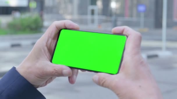 Alter Mann beobachtet Smartphone mit Chroma-Bildschirm, im Freien — Stockvideo