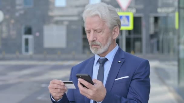 Viejo hombre de negocios de compras en línea en Smartphone mientras está parado al aire libre — Vídeos de Stock