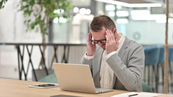 Gestresster junger Mann mit Laptop hat Kopfschmerzen im Büro — Stockfoto