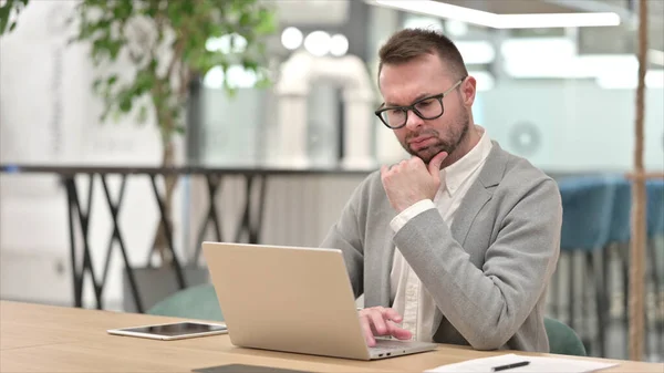 Pensive Kaukasische jongeman denken en werken op laptop in Office — Stockfoto