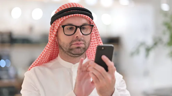 Portret poważnego młodego Araba Przeglądającego Internet na smartfonie — Zdjęcie stockowe