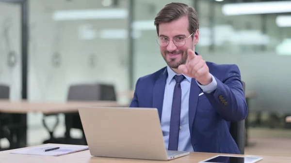 Jovem empresário com laptop apontando para a câmera — Fotografia de Stock