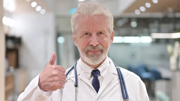 Портрет веселого старого лікаря показує великі пальці вгору — стокове фото